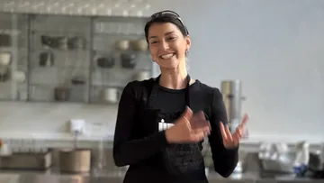 Lächelnde Frau klatscht in moderner Küche.
