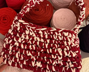 Woven red and white bag with yarn rolls.