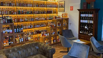 Whiskey bottles on shelves in cozy room.