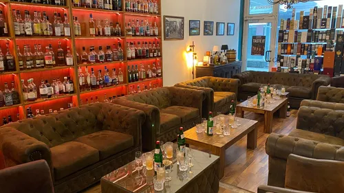 Shelves of whiskey bottles, lounge area with couches.