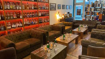 Cozy whisky lounge with leather couches, bottles displayed.