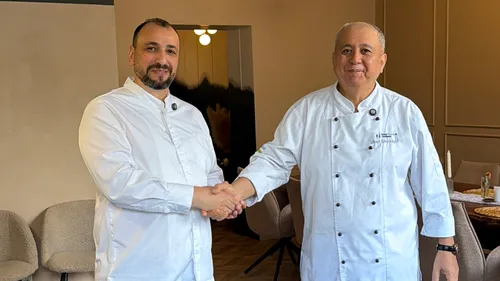 Two chefs shaking hands in a dining room.