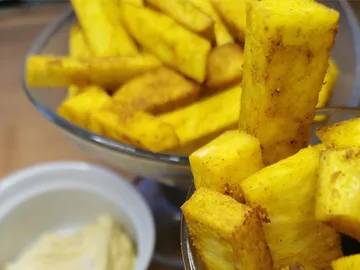 Knusprige, gewürzte Pommes in einer Schüssel neben Dip.