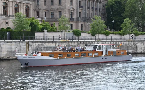 Tour boat sailing beside historic building.