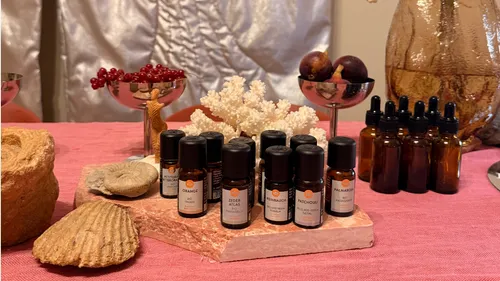 Aromatherapieöle auf rosa Tisch angeordnet.