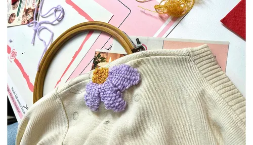Fabric with embroidered flower, crafting tools.
