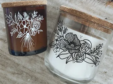 Zwei Kerzen stehen auf einer Oberfläche, floral dekoriert.