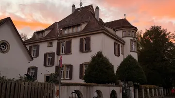 Historic mansion under a vibrant sunset sky.