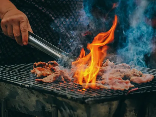 Meat is cooked over an open fire on a grill.