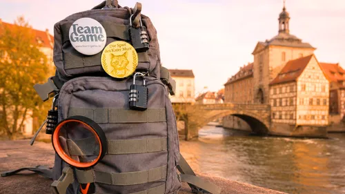 Rucksack mit Schlössern und Pins in Stadtlandschaft.