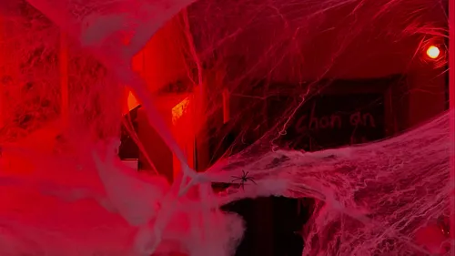 Spinne inmitten von Spinnweben im rot beleuchteten Raum.
