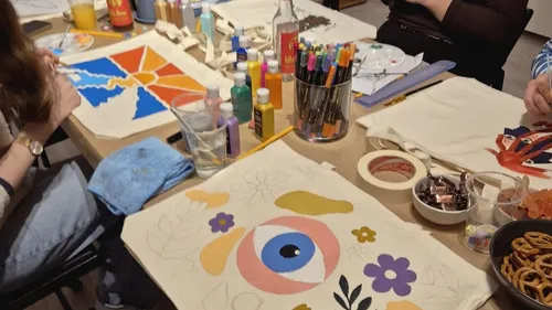 Menschen bemalen Taschen an einem Tisch.