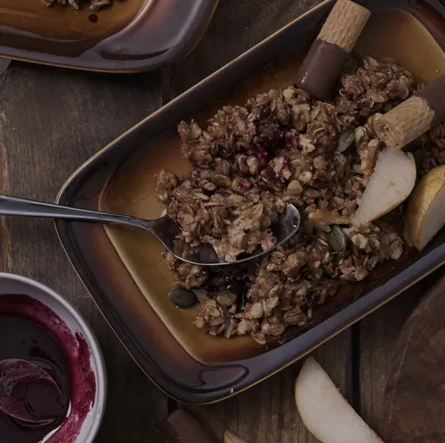 Granola-Dessert auf Teller mit Löffel und Beeren.