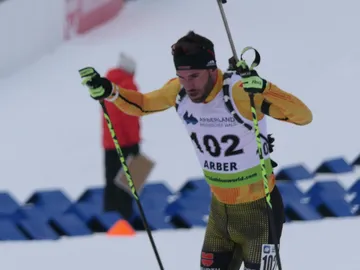 Skilangläufer stürzt sich mit Skistöcken in den Schnee.