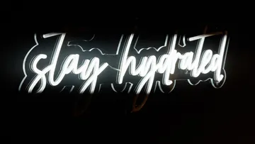 Neon sign displaying 'stay hydrated' in darkness.