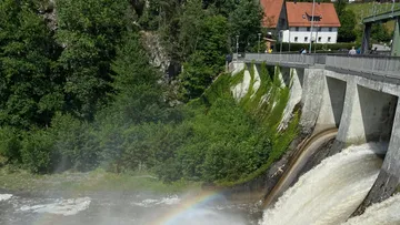 Dam releasing water with a rainbow nearby.