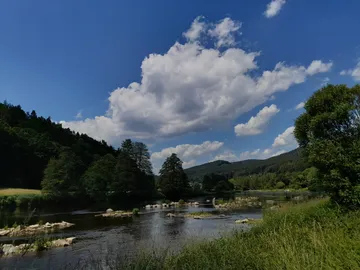 River flows quietly under a blue sky with clouds.