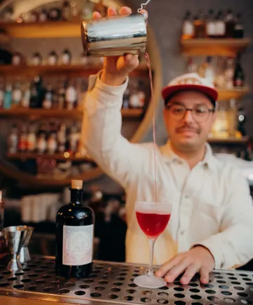 Barkeeper gießt roten Cocktail in Bar ein.