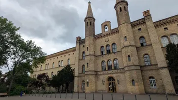 Historic building with towers, cloudy sky.
