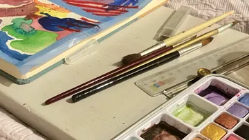 Paintbrushes and watercolor set on a table.