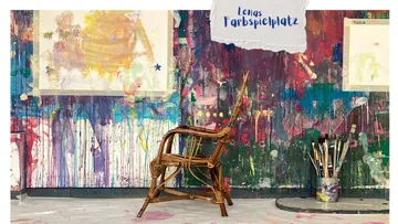 Chair on paint-splattered floor, colorful wall.