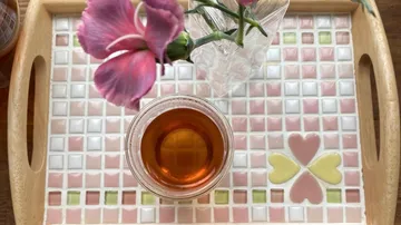 Glass of tea and flower on mosaic tray