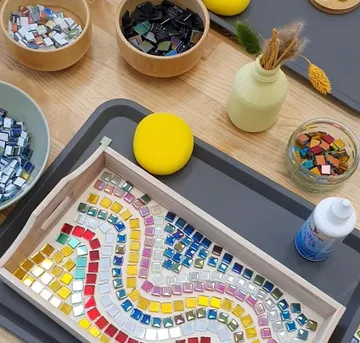 Mosaic tiles arranged on a wooden tray.