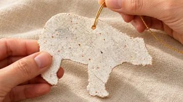 Hand holds bear-shaped seed paper ornament.