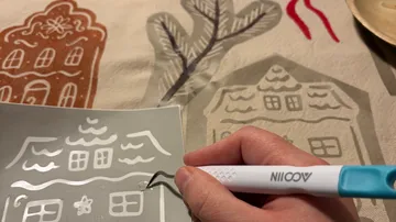Hand holds tool on stencil sheet.