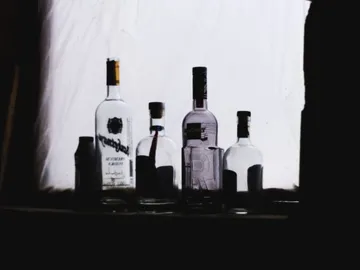 Bottles stand on a surface against a bright background.