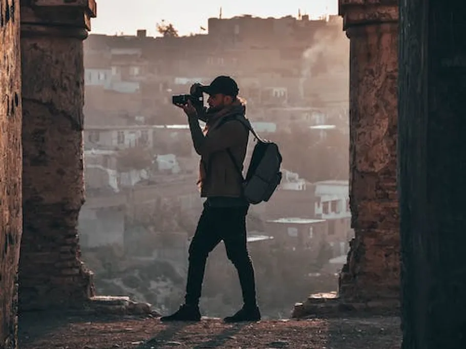 A photographer stands in a gate and takes pictures.