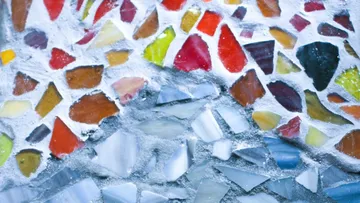 Colorful mosaic tiles against a cement background.