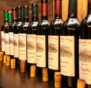 Wine bottles lined up on wooden surface.