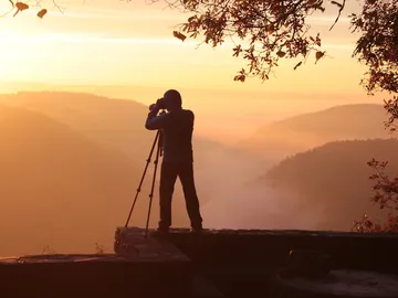 Person fotografiert Landschaft bei Sonnenaufgang in den Bergen.