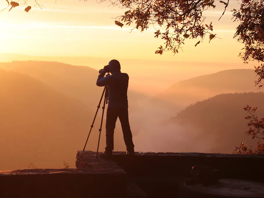 Person taking pictures of landscape at sunrise in the mountains.