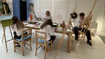Artists painting at tables in a studio.