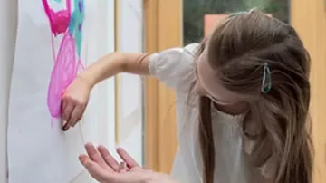Child painting with fingers indoors.
