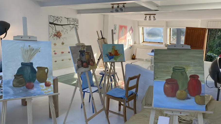 Paintings on easels in a bright studio.