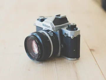 The camera is lying on a wooden surface and shows the manufacturer.
