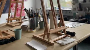 Staffelei auf Tisch mit Malutensilien.