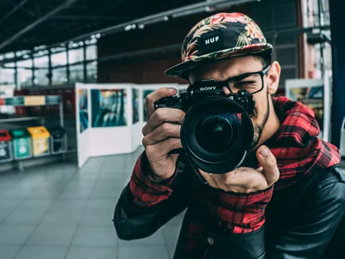 Boy holds camera, takes photo in an open environment.