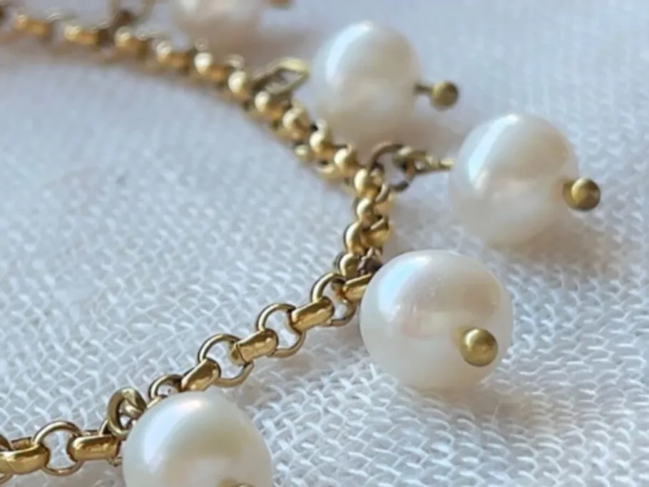 A pearl necklace lies on a white, textured background.