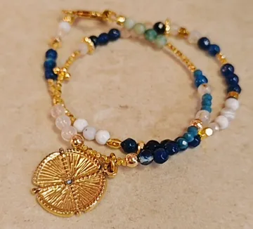 Perlenarmband mit Goldanhänger auf Oberfläche.