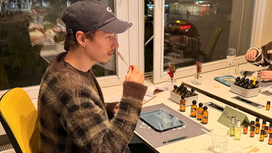 Person smelling perfume strips in lab setting.
