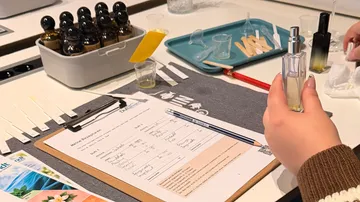 Person mixing fragrances on a table.