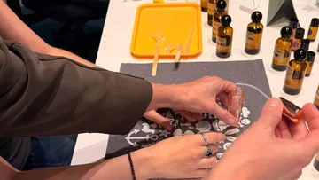 Hands crafting with bottles on a table.