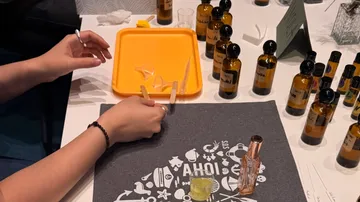 Hands blending oils at workshop table.