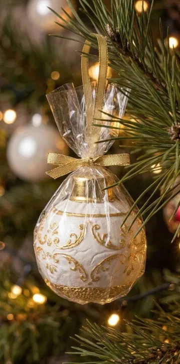 Ornate Christmas ornament hangs on decorated tree.