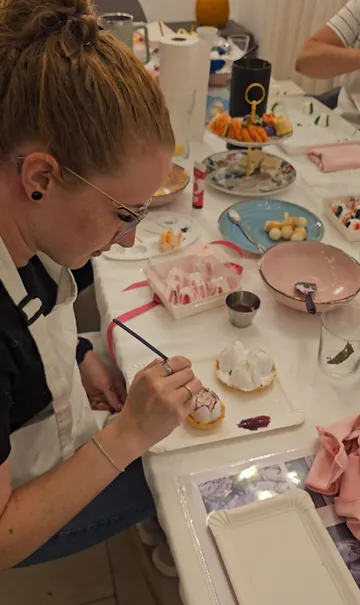 Person paints desserts at creative workshop.