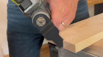 Power tool cutting wooden board indoors.